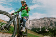 A man rides a mountain bike along a dirt road surrounded by trees and rugged terrain