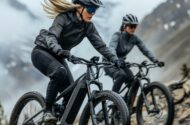 Two women riding mountain bikes along a rocky trail surrounded by trees and rugged terrain